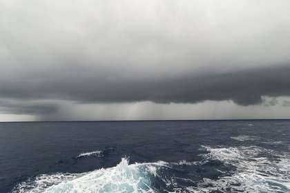 Sea with dark cloudy sky and rain in the distance